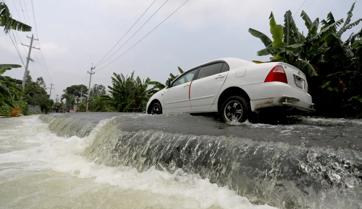 Mobil menembus jalan yang terendam banjir di Munshiganj, pinggiran Dhaka, Bangladesh, Senin (27/7/2020). Hingga 27 Juli 2020, hampir separuh dari wilayah Bangladesh masih terendam banjir. (Xinhua)