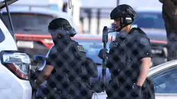 Petugas menyiapkan perlengkapan mereka di dekat lokasi penembakan di San Jose, California (26/5/2021). Fasilitas itu merupakan pusat kontrol transit tempat penyimpanan dan pemeliharaan kereta-kereta LRT. (AP Photo/Noah Berger)