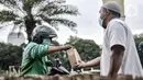 Petugas membagikan takjil kepada pengendara secara drive thru di Kompleks Masjid Al-Azhar, Jakarta, Selasa (13/4/2021). Pengelola Masjid Al-Azhar menyiapkan 500 bungkus takjil per hari yang dibagikan secara drive thru guna mencegah penyebaran COVID-19. (merdeka.com/Iqbal S. Nugroho)