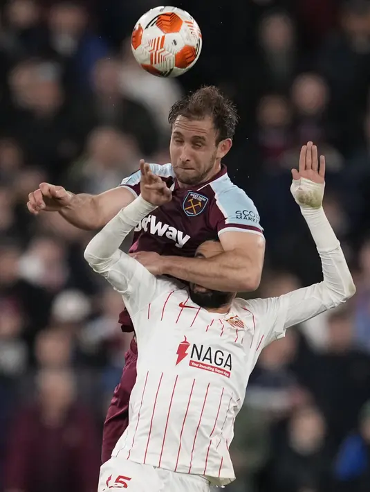 Bek West Ham Craig Dawson dan penyerang Sevilla Sevilla Youssef En-Nesyri menyundul bola saat bersaing pada leg kedua Liga Europa 2021/2022 di Stadion London, Jumat (18/3/2022) dini hari WIB. West Ham United menang dramatis atas Sevilla dengan skor 2-0. (AP Photo/Matt Dunham)