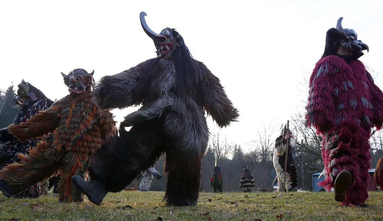 Sejumlah peserta mengenakan kostum iblis menari saat parade tardisional Perchtenlauf di Osterseeon dekat Munchen, Jerman (17/12). Acara ini bertujuan untuk mengusir hantu-hantu musim dingin. (Reuters/Michaela Rehle)