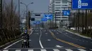 Pengendara sepeda motor terlihat di jalanan yang sepi dekat kantor pusat Alibaba di Kota Hangzhou, Provinsi Zhejiang, China, Rabu (5/2/2020). Pemerintah Hangzhou memberlakukan pembatasan pergerakan bagi warganya menyusul mewabahnya virus corona. (NOEL CELIS/AFP)