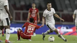 Gelandang Persija Jakarta, Riko Simanjutak, berebut bola dengan gelandang Madura United, Marchkho Merauje, pada laga Shopee Liga 1 di SUGBK, Jakarta, Jumat (13/12). Persija menang 4-0 atas Madura. (Bola.com/Yoppy Renato)