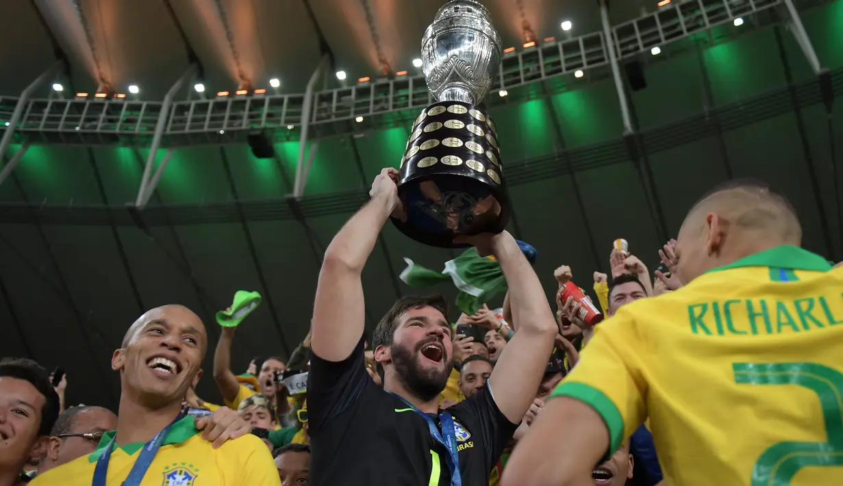 Kiper Timnas Brasil, Alisson mengangkat trofi Copa America 2019 saat berselebrasi bersama rekan setimnya setelah mengalahkan Peru pada partai final di Maracana Stadium, Rio de Janeiro, Senin (8/7/2019) dini hari WIB. Brasil menundukkan Peru dengan skor 3-1. (Carl DE SOUZA/AFP)