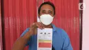 Pengemudi bus menunjukkan surat keterangan mengemudi usai tes urine di Terminal Kampung Rambutan, Jakarta, Kamis (24/3/2022). Pemeriksaan kesehatan dan tes urine dilakukan secara rutin setiap bulan yang bertujuan untuk memastikan kesehatan pengemudi. (Liputan6.com/Herman Zakharia)