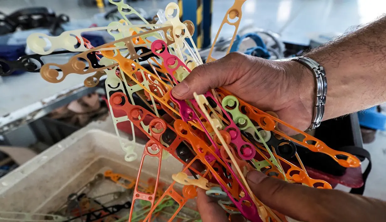 Pekerja menunjukkan bahan pendukung untuk membuat pelindung wajah di perusahaan Plaxtil, Chatellerault, Prancis, 25 Agustus 2020. Startup di Prancis, Plaxtil, mendaur ulang masker dan plastik untuk dijadikan pelindung wajah, pembuka pintu, dan pengencang masker. (GUILLAUME SOUVANT/AFP)