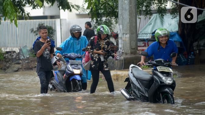 Pengendara mendorong sepeda motor mereka saat melewati banjir yang merendam Jalan Ahmad Yani, Jakarta, Sabtu (8/2/2020). Hujan yang mengguyur Jakarta sejak semalam membuat sejumlah ruas jalan terendam banjir. (merdeka.com/Imam Buhori)