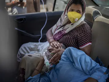 Seorang pasien bernapas dengan bantuan oksigen yang disediakan oleh tempat ibadah Gurdwara, Sikh, di dalam sebuah mobil di New Delhi pada 24 April 2021. India mengalami kekurangan oksigen yang kritis di tengah badai infeksi Covid-19 yang menghancurkan sistem kesehatannya. (AP Photo/Altaf Qadri)