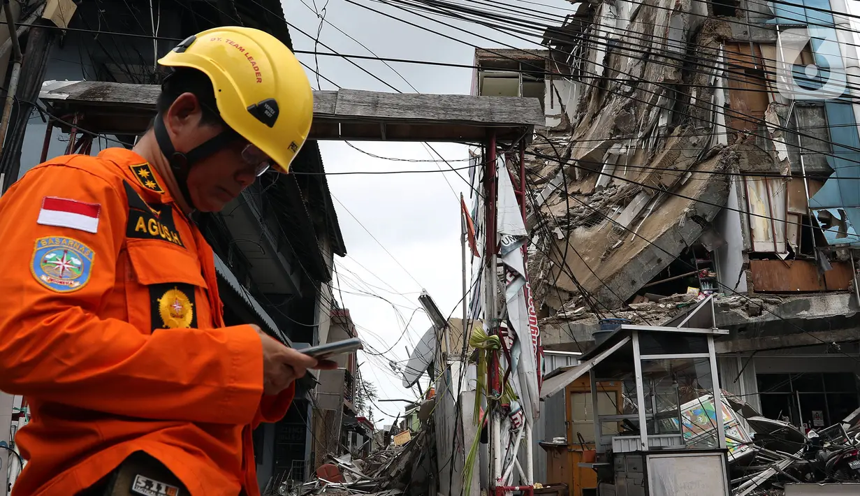 Petugas Basarnas berdiri dekat gedung yang ambruk di Jalan Brigjen Katamso, Kota Bambu Selatan, Palmerah, Jakarta Barat, Senin (6/1/2020). Tiga orang dilaporkan terluka akibat tertima material gedung empat lantai tersebut. (Liputan6.com/Johan Tallo)