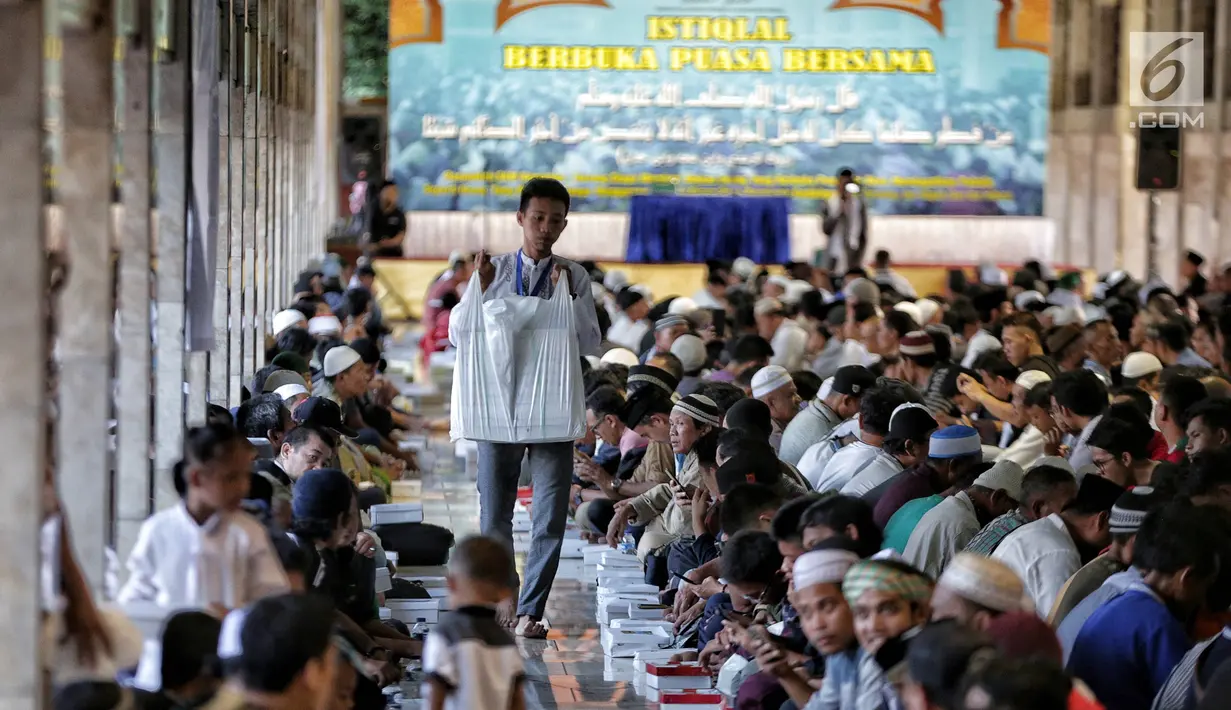Panitia membagikan nasi kotak jelang buka puasa bersama di Masjid Istiqlal, Jakarta, Senin (6/5/2019). Kaum perempuan dan anak-anak duduk terpisah dengan lelaki. (Liputan6.com/Faizal Fanani)