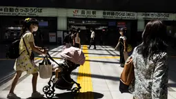 Komuter memakai masker sambil mendorong kereta bayi di stasiun kereta api di Tokyo saat keadaan darurat virus corona tetap berlaku di kota itu pada Selasa (10/8/2021).  Pemerintah Metropolitan Tokyo mengonfirmasi 2.884 kasus baru covid-19 pada Senin, 9 Agustus 2021. (Yuki IWAMURA / AFP)