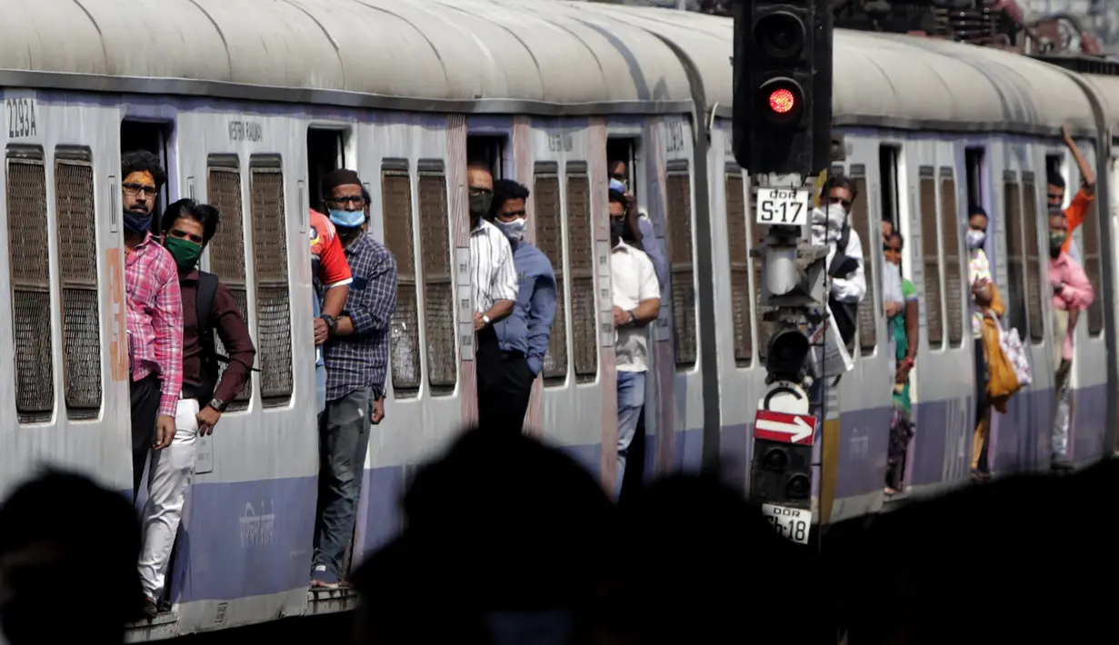 Orang-orang bepergian dengan kereta api lokal, banyak yang mengenakan masker di bawah hidung, di Mumbai, India, pada 12 Januari 2022. Wajib pakai masker di India. Dan polisi turun ke jalan, mengawasi orang-orang untuk memastikan mereka ada di tempat. (AP Photo/Rajanish kakade)