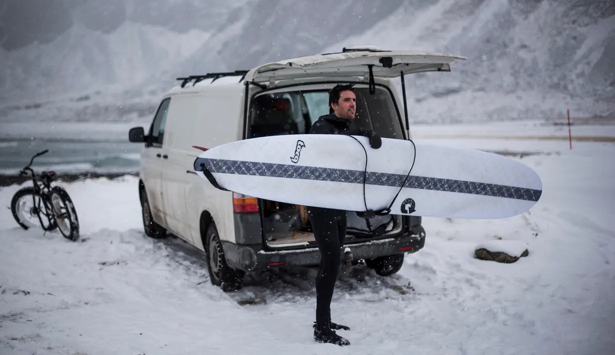 Seorang surfer membawa papannya bersiap berselancar di Unstad, Norwegia Utara (10/3). Surfer ini berselancar di wiliyah Lingkaran Arktik dengan suhu minus 13 derajat Celsius. (AFP Photo/Olivier Morin)
