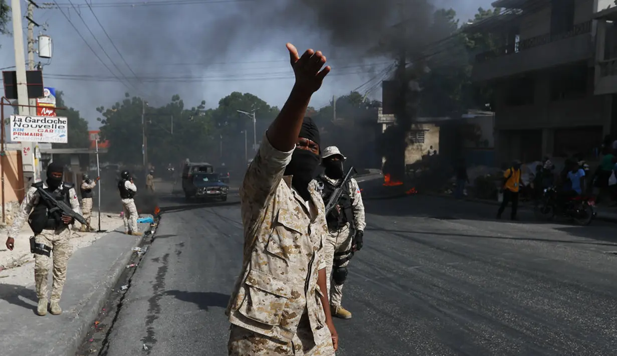 Polisi membersihkan pembatas jalan yang dibakar oleh para pengunjuk rasa yang marah dengan meningkatnya kekerasan di lingkungan Lalue, Port-au-Prince, Haiti, Rabu (14/7/2021). Presiden Haiti Jovenel Moise dibunuh pada 7 Juli. (AP Photo/Fernando Llano)