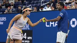 Petenis Indonesia, Aldila Sutjiadi (kiri) memberikan bola kepada petenis India, Rohan Bopanna saat bertanding melawan petenis ganda campuran Amerika Serikat, Taylor Townsend/Donald Young pada laga semifinal US Open 2024 yang berlangsung di di Stadion Louis Amstrong, New York, Amerika Serikat, Rabu (04/09/2024) WIB. (AP Photo/Eduardo Munoz Alvarez)