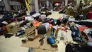Turis asing bersantai dengan alas seadanya di lantai Bandara Internasional Lombok Praya, NTB, Senin (6/8). Imbas gempa 7 skala Richter, para wisatawan mancanegara terlantar di bandara karena jam pemberangkatan pesawat yang tertunda. (AFP/SONNY TUMBELAKA)