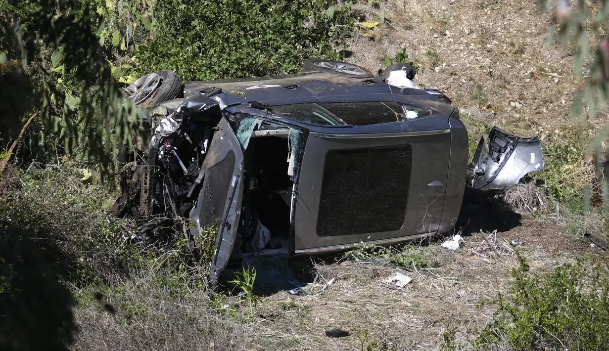 Sebuah crane digunakan untuk mengangkat mobil pegolf Tiger Woods setelah kecelakaan di Rancho Palos Verdes, California, pinggiran Los Angeles, Selasa (23/2/2021). Kendaraan yang dibawa Woods keluar dari jalan raya dan terguling ke lereng sebelum berhenti di dasar jurang. (AP Photo/Mark J. Terrill)