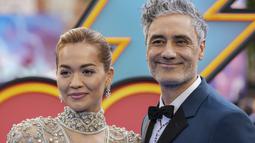Rita Ora bersama tunangannya sutradara Taika Waititi berpose saat tiba menghadiri pemutaran film 'Thor: Love and Thunder di London (5/7/2022). Tak ketinggalan sepasang anting berlian membuat penampilan Rita Ora makin berkilau. (AP Photo/Scott Garfitt)