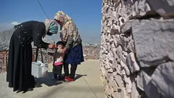 Tenaga kesehatan (kiri) memberikan vaksin polio kepada seorang anak selama kampanye vaksinasi di kawasan tua Kabul, Afghanistan pada 8 November 2021. Vaksinasi tersebut merupakan yang pertama sejak Taliban berkuasa di Afghanistan. (WAKIL KOHSAR / AFP)
