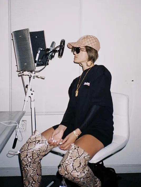 Kacamata rupanya jadi salah satu fashion item andalan Agnez Mo. Ketika sedang menjalani rekaman sebuah lagu, ia tampil swag dengan kaus panjang yang dipadukan dengan sepatu boot bermotif serta topi dan kacamata hitam.(Liputan6.com/IG/@agnezmo)