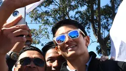 Pembalap Manor Racing, Rio Haryanto berselfie dengan penggemarnya menjelang debut pada ajang Formula 1 di GP Australia, Melbourne, Minggu (20/3). Akibat mendapat hukuman, Rio Haryanto harus memulai Grand Prix Australia dari posisi buncit. (Paul Crock/AFP)