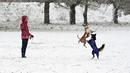 Seorang wanita melihat anjing bermain di taman saat salju pertama turun di Kota Lviv, Ukraina, 17 November 2022. Salju pertama musim ini turun di tengah invasi Rusia ke Ukraina. (YURIY SEMCHYSHYN/AFP)