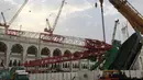 Pekerja dibantu alat berat berusaha mengevakuasi crane yang roboh di Masjidil  Haram, Kota Mekah,  Arab Saudi (9/12/2015). Sebanyak 107 calon jemaah haji meninggal dunia akibat crane jatuh karena cuaca buruk. (AFP PHOTO / STR)