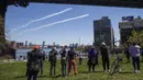Warga menyaksikan skuadron jet tempur Blue Angels dari Angkatan Laut dan Thunderbirds dari Angkatan Udara Amerika Serikat bermanuver di langit Kota New York, Selasa (28/4/2020). Aksi itu sebagai bentuk penghormatan untuk petugas medis yang tengah berjuang melawan COVID-19. (AP Photo/Mary Altaffer)
