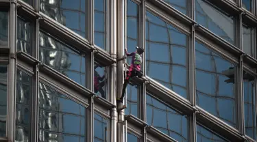 Alain Robert yang dijuluki 'French Spiderman' memanjat gedung pencakar langit Cheung Kong Center di Hong Kong, Jumat (16/8/2019). Pria berusia 57 tahun tersebut memanjat Cheung Kong Center dalam kondisi panas dan lembab pada Jumat pagi. (Lillian SUWANRUMPHA/AFP)