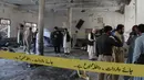 Petugas penyelamat dan aparat kepolisian memeriksa lokasi ledakan bom di sebuah madrasah di kota Peshawar, Pakistan, Selasa (27/10/2020). Lebih dari 60 orang sedang ada di ruang salah satu kelas saat itu, ketika ledakan mengguncang pada Selasa  pagi. (AP Photo/Muhammad Sajjad)