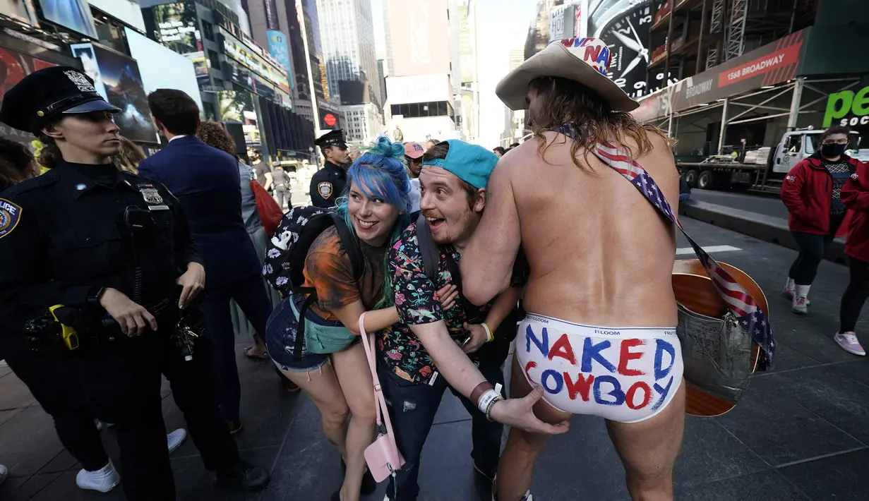 Wisatawan berpose dengan Naked Cowboy di Times Square, New York pada 9 November 2021. Turis asing yang mendatangi Amerika Serikat disambut kembali ke New York City untuk pertama kalinya dalam 20 bulan setelah pembatasan perjalanan pandemi Covid-19 dicabut. (TIMOTIUS A. CLARI / AFP)