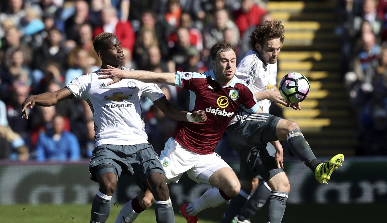 Pemain Burnley, Ashley Barnes (tengah) menerobos adangan pemain Manchester United, Paul Pogba dan Daley Blind pada lanjutan Premier League di Turf Moor Stadium, Burnley, Minggu (23/4/2017). MU menang 2-0.  (Martin Rickett/PA via AP)