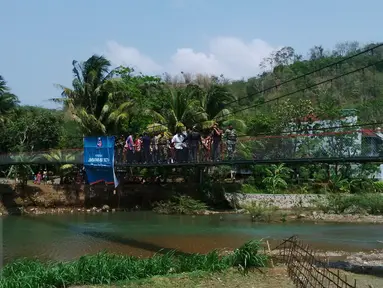 Perwakilan SCTV dan warga berjalan diatas jembatan Asa SCTV ke-5 yang ada di Desa Sirna Bakti Kec. Pamengpeuk Kab Garut, Sabtu (14/11/2015). (Dokumentasi SCTV)