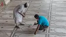 Pengurus menempelkan stiker di lantai bagi jemaah agar menjaga jarak selama salat ketika Masjid Jama dibuka kembali setelah pelonggaran lockdown di kawasan Kota Tua Delhi, Selasa (7/7/2020). India pada 6 Juli menjadi negara dengan jumlah virus corona tertinggi ketiga di dunia. (XAVIER GALIANA/AFP)