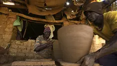 Seorang perajin Sudan membentuk sepotong tembikar di sebuah bengkel di Omdourman, di pinggiran barat ibu kota Khartoum (19/1/2022). Pot tanah liat tersebut nantinya akan dipajang untuk dijual. (AFP/Ashraf Shazly)