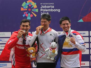 Atlet BMX Indonesia, I Gusti Bagus Saputra (kiri) mengigit medali  usai bertanding pada nomor putra di Pulo Mas International BMX Center, Sabtu (25/8). Bagus Saputra meraih medali perak. (Liputan6.com/Fery Pradolo)