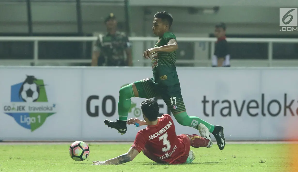 Pemain depan PS TNI, Ahmad Nufiandani melompat menghindari tekel bek Arema FC, Jad Noureddine saat laga lanjutan Liga 1 Indonesia di Stadion Pakansari, Bogor, Senin (3/7). Laga kedua tim berakhir imbang 0-0. (Liputan6.com/Helmi Fithriansyah)