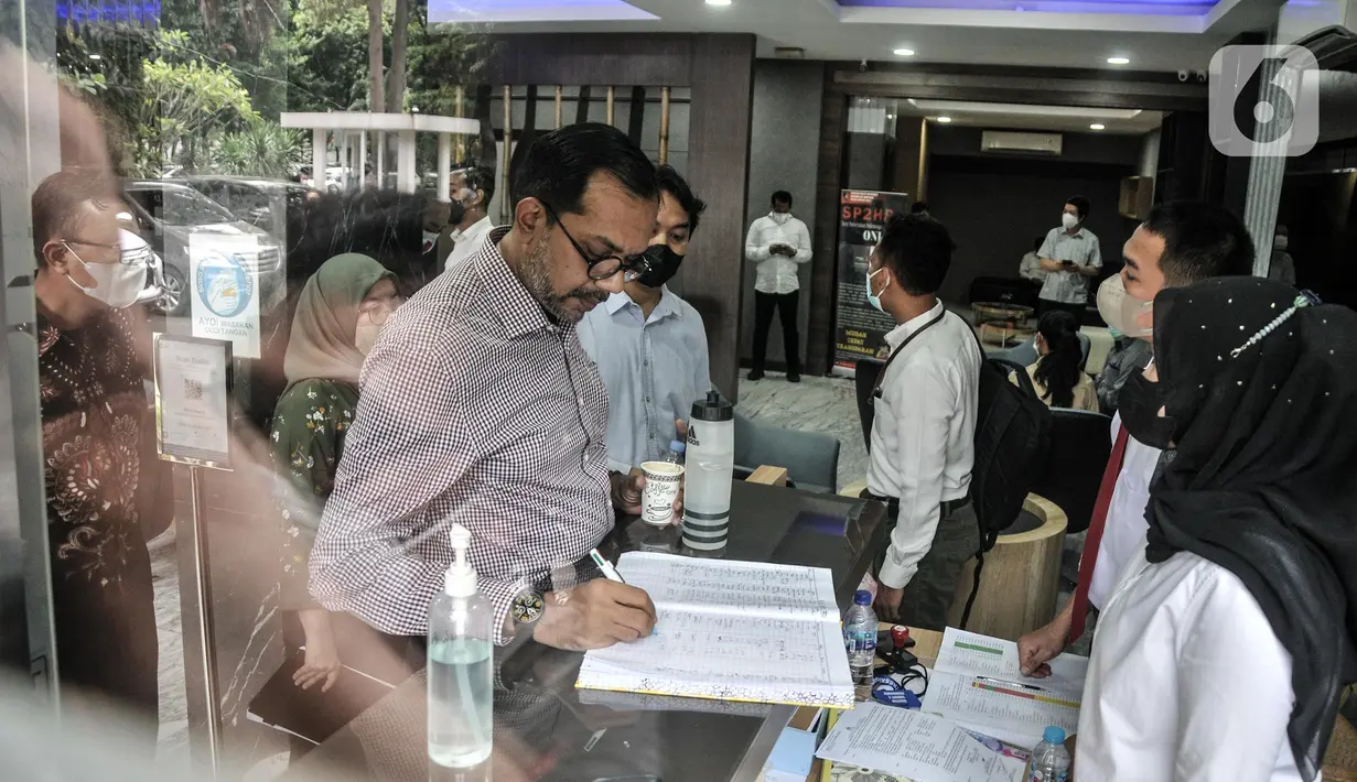Direktur Lokataru Haris Azhar menulis pada sebuah buku saat tiba di Polda Metro Jaya, Jakarta, Senin (21/3/2022). Luhut Binsar Pandjaitan melaporkan tayangan yang diunggah akun Youtube Haris Azhar pada 20 Agustus 2021. (merdeka.com/Iqbal S. Nugroho)