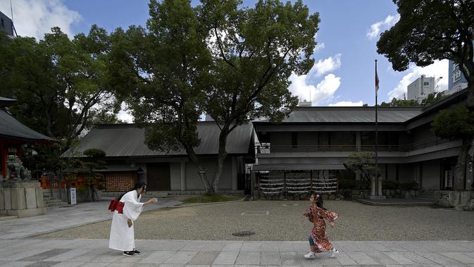Seorang wanita memfoto anaknya saat mengunjungi Kuil Ikuta terlihat di pusat Kobe (5/10/2019). Kuil, dengan sejarah lebih dari 1.800 tahun ini dikatakan sebagai salah satu kuil tertua di Jepang. (AFP Photo/Monteforte)