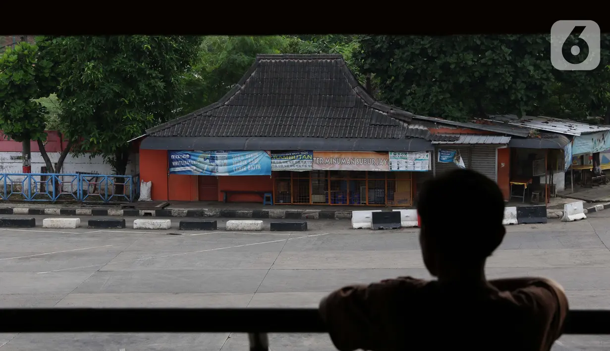 Seseorang melihat-lihat area parkir bus Antar Kota Antar Provinsi di Terminal Kampung Rambutan, Jakarta, Sabtu (25/4/2020). Untuk mencegah dan memutus mata rantai penularan virus Covid-19, pemerintah resmi melarang aktivitas mudik pada Jumat (24/4) lalu. (Liputan6.com/Helmi Fithriansyah)