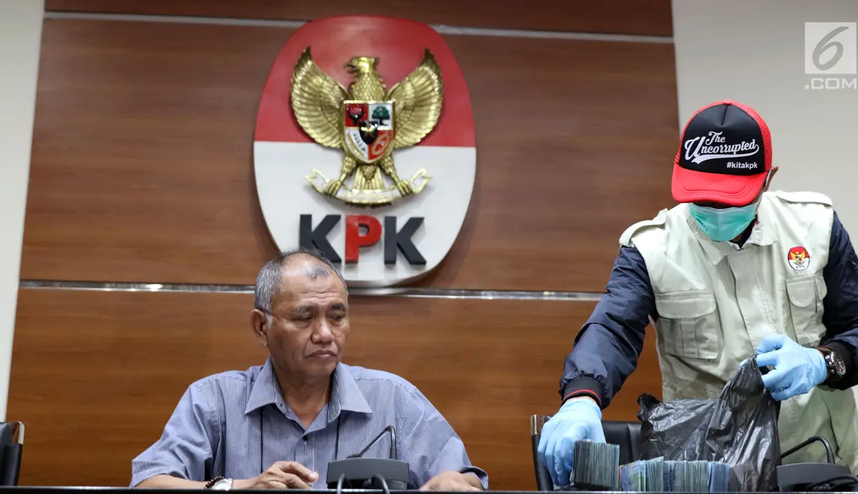 Ketua KPK Agus Rahardjo (kiri) melihat barang bukti hasil OTT Bupati Pakpak Bharat Sumatera Utara, Remigo Yolanda Berutu di Gedung KPK, Jakarta, Minggu (18/11). KPK menetapkan tiga tersangka dan menyita uang Rp 150 juta. (Liputan6.com/Helmi Fithriansyah)