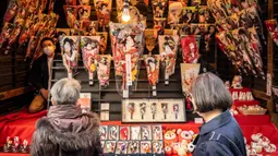 Orang-orang melihat battledore kayu Jepang yang disebut 'hagoita' pada pekan raya akhir tahun di Distrik Nihonbashi, Tokyo, Jepang, 26 Desember 2022. Tak hanya menyuguhkan pemandangan indah dan makanan yang lezat, Jepang juga menjadi negara yang tepat untuk merayakan tahun baru. (Yuichi YAMAZAKI/AFP)
