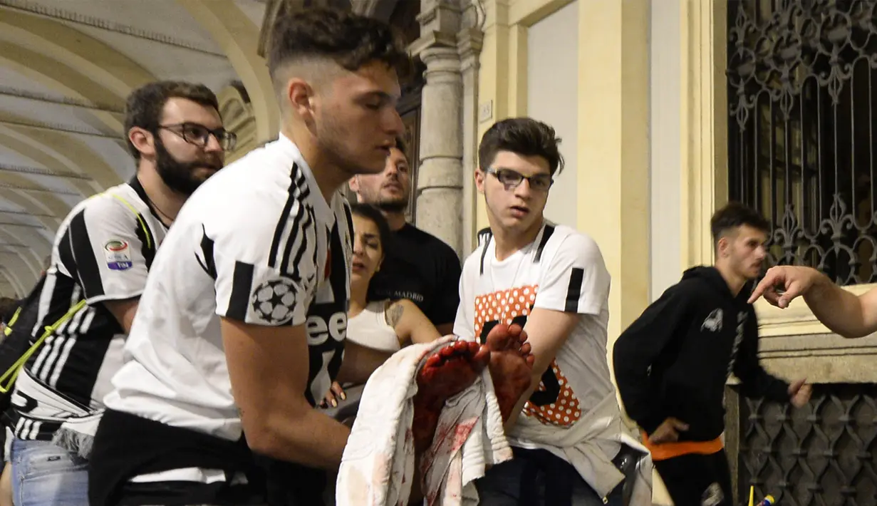 Para supporter saling bantu mengevakuasi usai terjadi ledakan saat nonton bareng final Liga Champions di Piazza San Carlo, Turin, Sabtu (3/6/2017). Acara nobar dipadati sekitar 20.000 supporter Juventus. (AFP/Massimo Pinca)