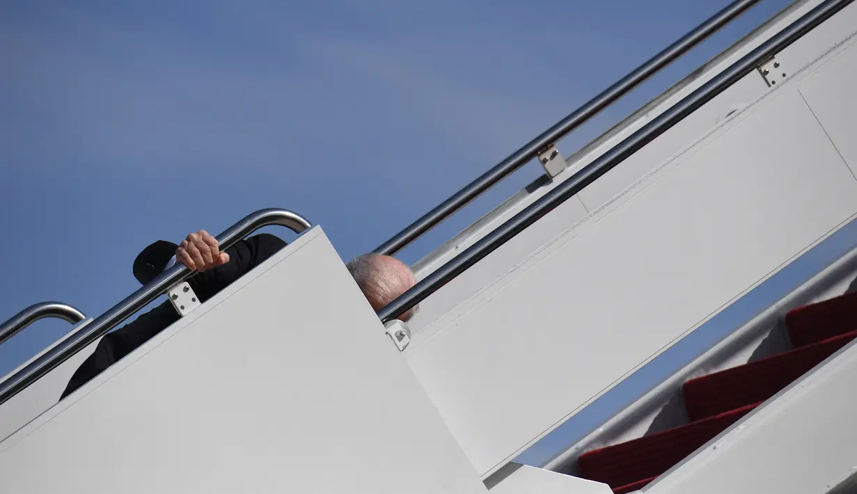 Presiden Amerika Serikat, Joe Biden saat menaiki Air Force One di Pangkalan Udara Andrews, Maryland, Jumat (19/3/2021). Berusia 78 tahun, Joe Biden merupakan orang tertua yang dilantik sebagai presiden AS. (Eric BARADAT/AFP)