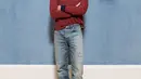 Joe Alwyn mengenakan polo Dior bergaris hitam dan merah, celana denim biru. Dipadu dengan kalung emas mawar, dan sepasang sepatu bot suede krem. [Dior]