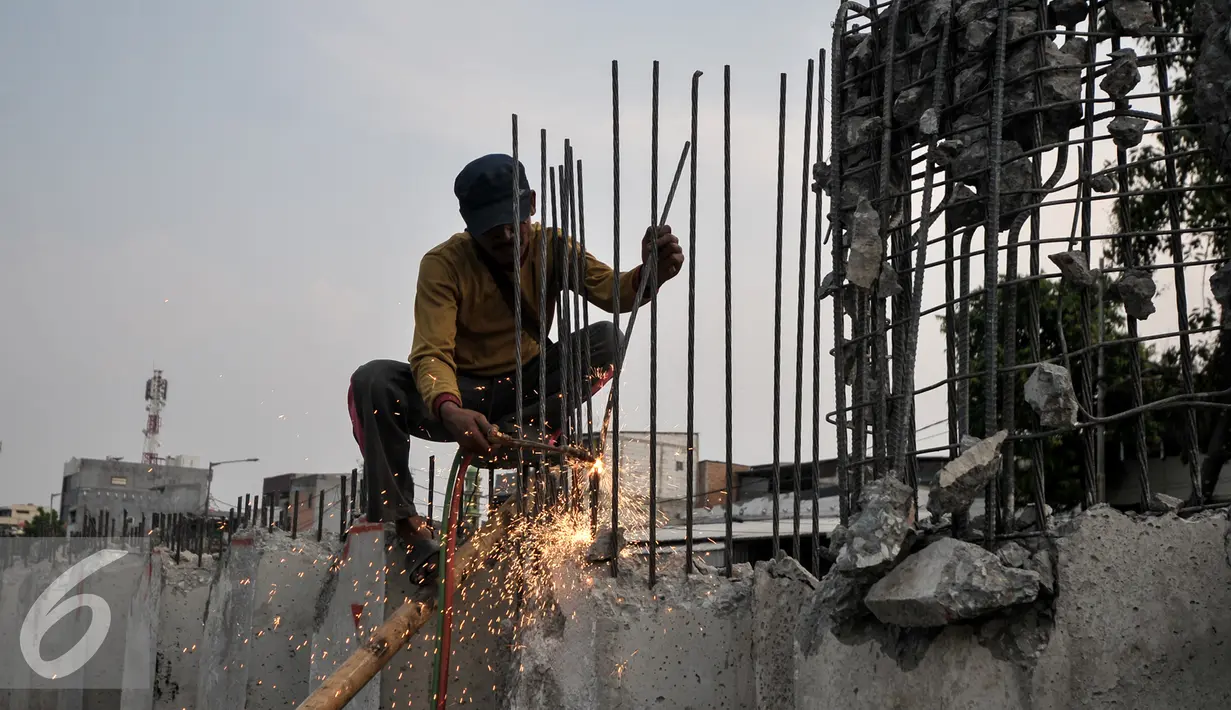Pekerja memotong besi sheet pile yang terpasang di Kali Sunter, Kemayoran, Jakarta, Selasa (26/7). Pemasangan turap terus dikebut untuk mencegah terjadinya banjir di musim penghujan.(Liputan6.com/Yoppy Renato)