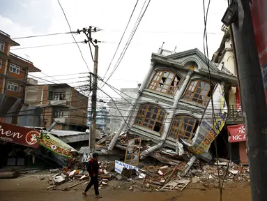 Foto yang diambil pada 1 Mei 2015 menunjukkan warga berjalan di dekat rumah yang runtuh setelah gempa 7,8 SR di Kathmandu. Setahun yang lalu, Nepal mengalami gempa terburuk dalam sejarah selama 80 tahun bencana di kawasan itu. (REUTERS/Navesh Chitrakar)