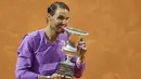 Petenis Spanyol, Rafael Nadal menggigit trofi juara turnamen tenis Italia Terbuka 2021 setelah mengalahkan petenis Serbia, Novak Djokovic di Foro Italico, Roma, Minggu (16/5/2021). Rafael Nadal menang dalam pertarungan tiga set 7-5, 1-6, dan 6-3 selama dua jam 49 menit. (AP Photo/Gregorio Borgia)