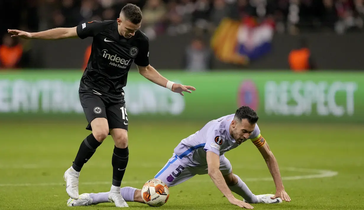 Penyerang Eintracht Frankfurt Rafael Santos Borre berebut bola dengan gelandang Barcelona Sergio Busquets pada laga leg pertama perempat final Liga Europa 2021/22 di Deutsche Bank Park, Jumat dini hari WIB (8/4/2022). Frankfurt dan Barcelona berbagi skor 1-1 . (AP Photo/Michael Probst)
