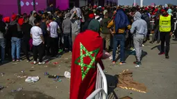 Seorang pria berbalut bendera Maroko mengantre dengan suporter di luar Stadion Al Janoub di Wakrah, dengan harapan mendapatkan tiket pertandingan sepak bola semifinal Piala Dunia 2022 antara Prancis vs Maroko, Selasa (13/12/2022). Partai hidup mati akan tersaji antara timnas Prancis melawan Maroko pada babak semifinal Piala Dunia 2022 di Stadion Al Bayt, Kamis (15/12) dini hari WIB. (AP Photo/Francisco Seco)